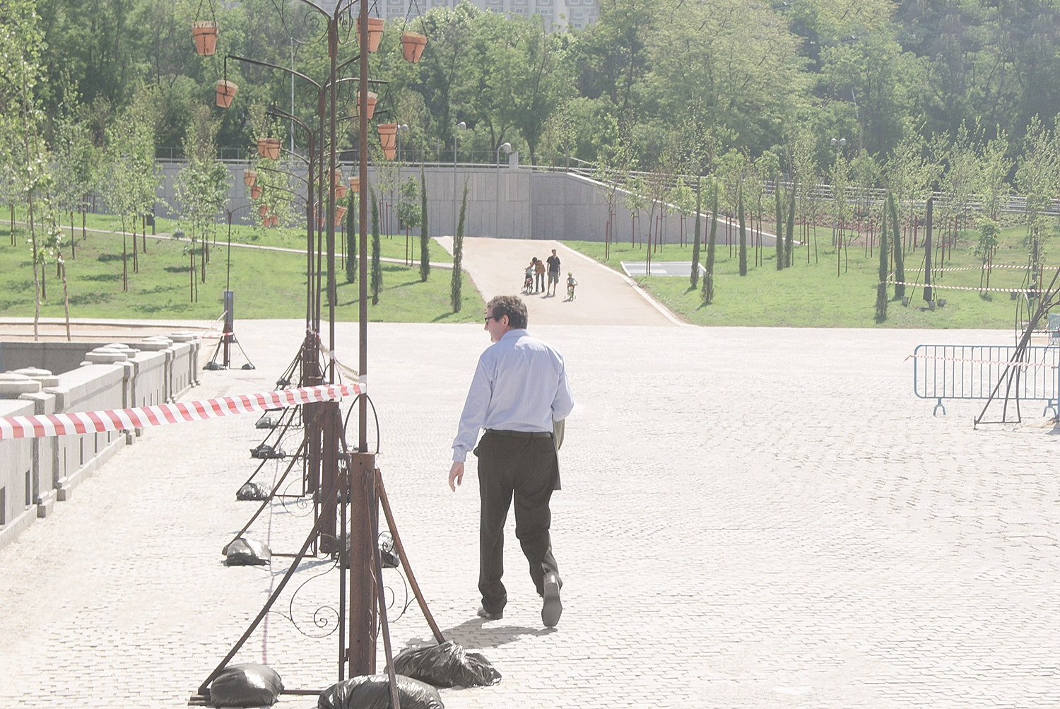 Man walking alone along wide paved path in park, A Man in a Park.