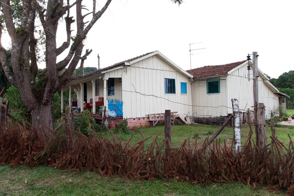 Modest countryside house surrounded by trees and dry vegetation, O Destino de Um Coração