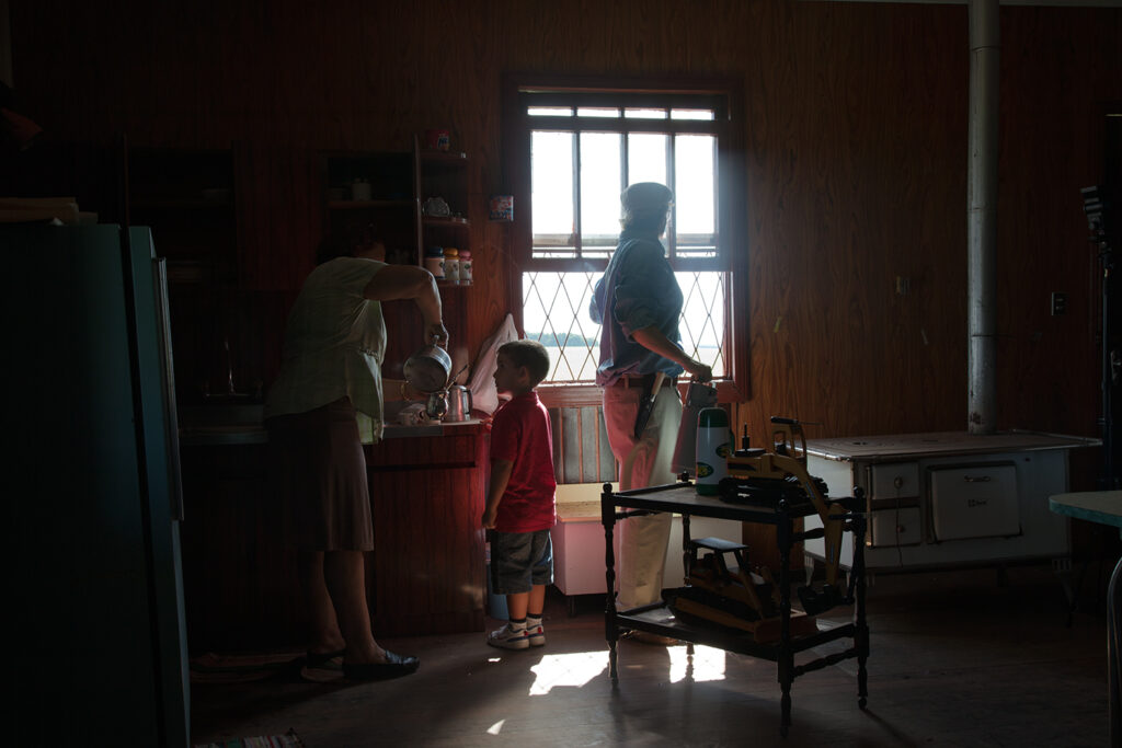 Dimly lit interior kitchen scene with family figures near a window, O Destino de Um Coração