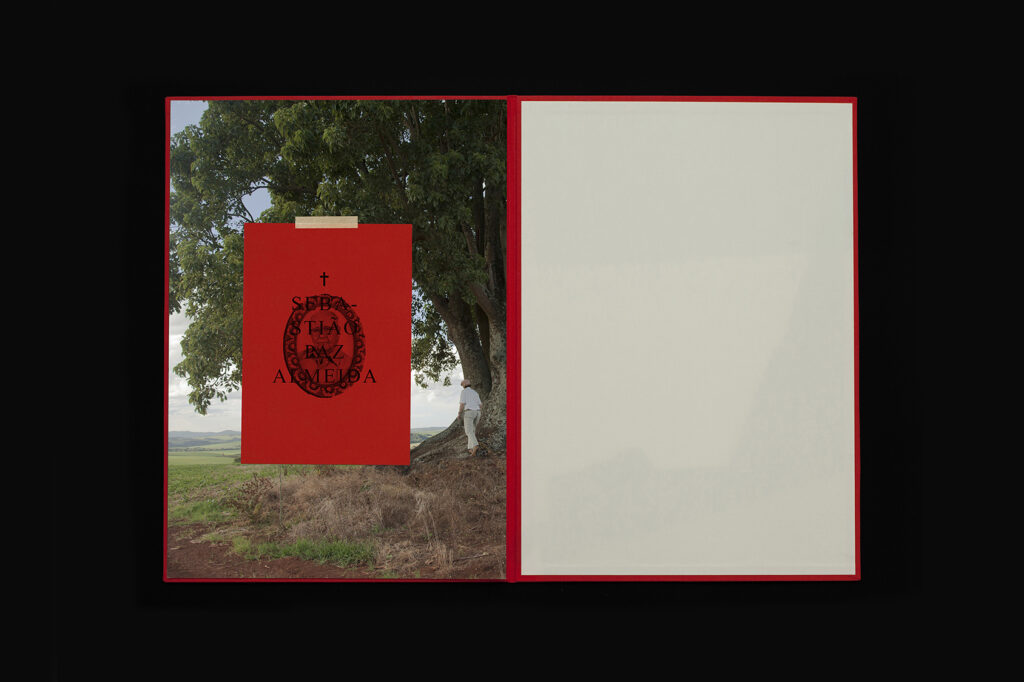 Photobook spread from O Destino de Um Coração showing red booklet over landscape page with blank facing page.
